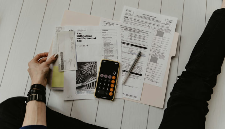 person holding paper near pen and calculator — illustrative stock photo