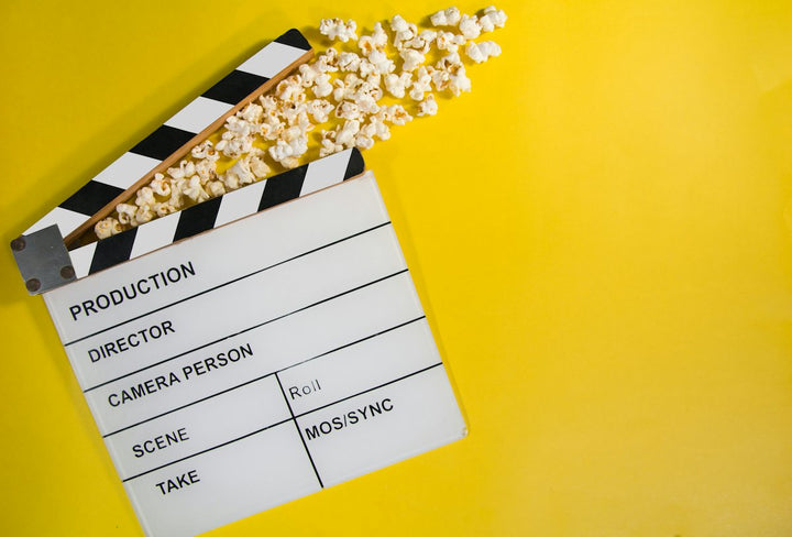 movie clapperboard with popcorn on yellow background — illustrative stock photo